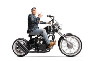 Fototapeta na wymiar Man in stylish clothes riding a chopper and gesturing rock and roll sign