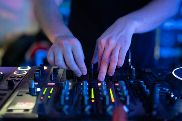 Close up Front view of of DJ hands controlling a music table in a night club. High quality photo
