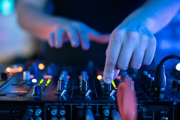 Close up Front view of of DJ hands controlling a music table in a night club. High quality photo