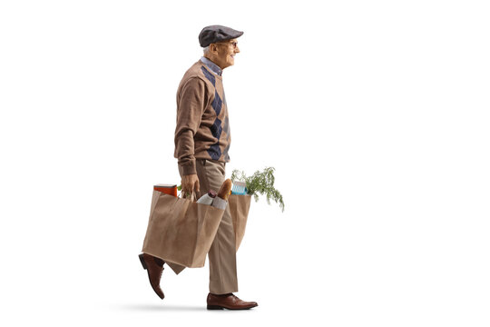 Full length profile shot of an elderly man carrying grocery bags and walking