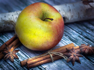 Apple with cinnamon sticks and star anise on the wooden surface 