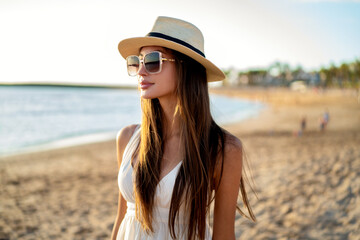 Portrait of brunette woman with long hair wearing fashionable sunglasses and hat. Tourism. Real people lifestyle.
