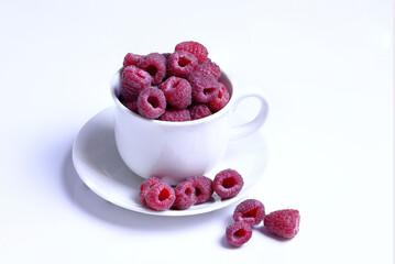 fresh raspberries in white cup sitting on the table, white background 