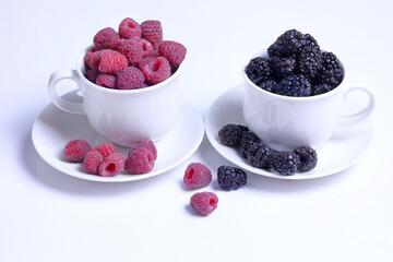 Raspberries and blackberries  in cups on the table., whit background, delicious and healthy snack, berries for smoothies, fitness breakfast.
