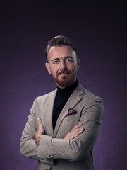 Obraz premium Portrait of a stylish elegant senior businessman with a beard and casual business clothes in photo studio isolated on dark background gesturing with hands