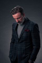 Fototapeta premium Portrait of a stylish elegant senior businessman with a beard and casual business clothes in photo studio isolated on dark background gesturing with hands