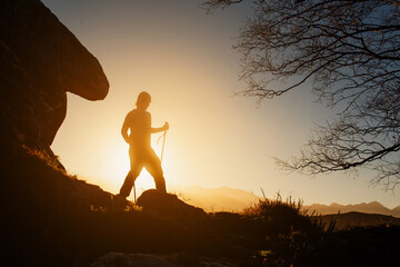 silhouette of man making a journey through the mountain. hiker at sunset.