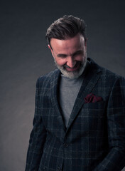 Obraz premium Portrait of a stylish elegant senior businessman with a beard and casual business clothes in photo studio isolated on dark background gesturing with hands