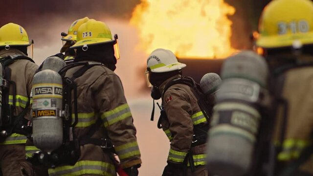 Dramatic shot of firefighters in formation putting out roaring fire in slow motion