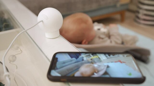 Smart IP camera is installed in the childrens room, indoor security camera works as a baby monitor. Parents watching baby in real-time on smartphone screen. High quality 4k footage