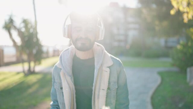 Young hispanic man smiling confident listening to music and dancing at park