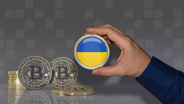 A hand holding a badge with the Ukrainian flag in front of some bitcoins. Crypto currency concept. - Powered by Adobe