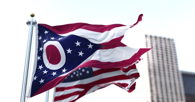 the flag of the US state of Ohio waving in the wind with the American flag blurred in the background