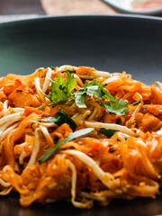 Thai Food Pad Thai (Thai national dish) Pad Thai on black plate with lime and seasonings.