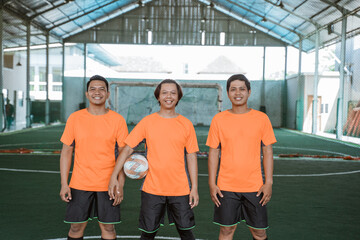 Three futsal players standing carrying the ball