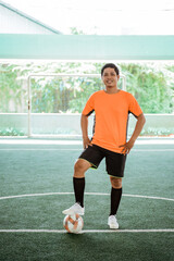Futsal player in orange uniform poses both hands on waist