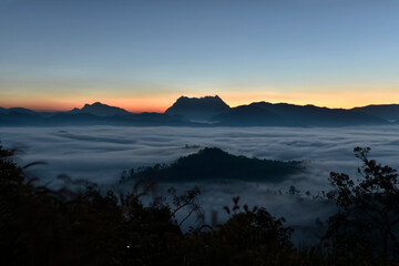 Fluffy sea of fog in a valley of Doi Luang Chiang Dao mountain with twilight sky background in sunrise time, Thailand