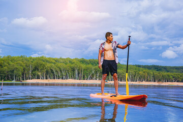 Young man have fun on stand up paddle board. Active paddle boarder paddling at the lake. Water...