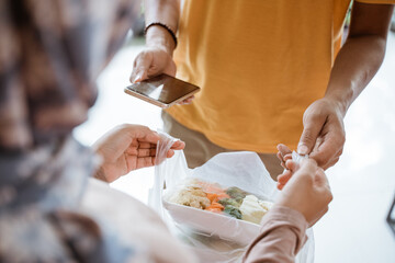 Deliveryman holding a cell phone while delivering vegetable orders