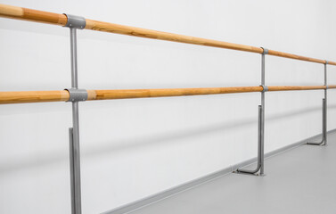 ballet barre in a studio with white walls. An empty ballet class, white walls, and a light wood bar 