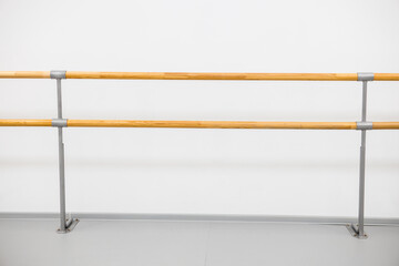ballet barre in a studio with white walls. An empty ballet class, white walls, and a light wood bar 