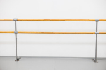 ballet barre in a studio with white walls. An empty ballet class, white walls, and a light wood bar 