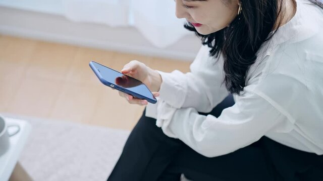 部屋でスマホを使う女性