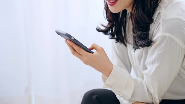 部屋でスマホを使う女性