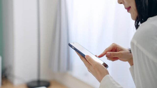 部屋でスマホを使う女性