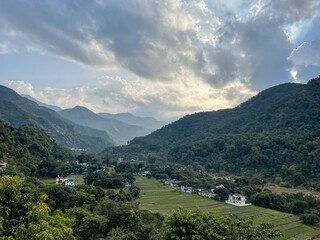 Obraz premium View of mountain landscape with fields in the valley and trees all around on the hills 