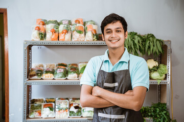 Smiling asian man with folded hands with vegetable products background