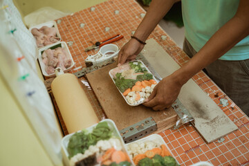 Hand of seller preparing vegetables using styrofoam plastic wrap