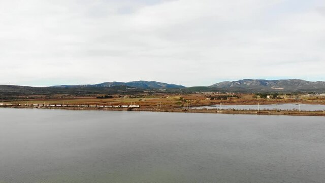 Aerial: goods train by the sea in southern France during winter. Camera going up