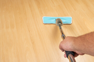 A Man mopping a light wooden floor. Copy space.