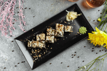 Golden dragon sushi roll with tuna, eel, cucumber, sesame seeds and tobiko caviar on wood background