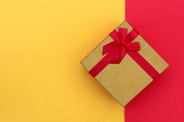 The gift box stands at the same time on the border of two colors, yellow and red.