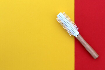 A white hair styling brush lies on a bright background.