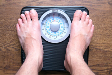 A man measures his weight and he stands on the scales. he has the right weight Concept of health and weight loss.