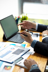 Businessman's hands holding a pen and pointing at a tablet screen.