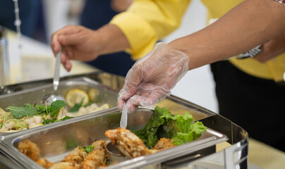a person wearing gloves scooping food, catering, dinner time, prevent Coronavirus disease (covid 19)