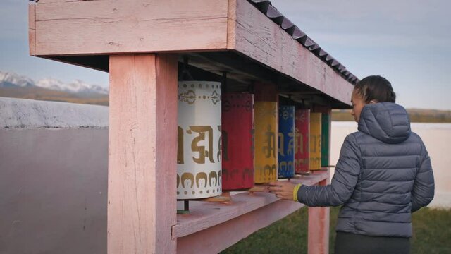 Buddhist prayer wheels drums in datsan. Woman tourist spinning a drums near the statue of the Buddha in Arshan. Buddhism.