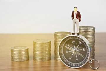 Compass,Businessman Figure miniature or small people and money coin on table. Concept business investment or Investment Direction.