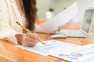 Close-up shot of A businesswoman holding a pencil checking data on a graph in the office