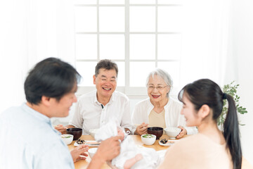 里帰り出産・食事をする老夫婦と若い夫婦
