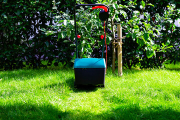 Back view on an electric lawn mower mowing down the long grass in a garden or backyard leaving a...