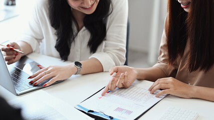 Two business people analyzing investment data in documents at office desk.