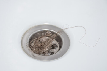 A bundle of women's loose hair was left in the bathroom drain after taking a shower. The problem of hair loss.