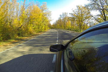 Naklejka premium Beautiful view from the side of a car driving on a country road. Blue sky and autumn trees. Travel concept.