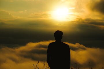 Silhouette man stands on top of the mountain and watching sunrise over the misty and foggy morning. Trendy destination travel on winter at Chiangmai, Thailand.