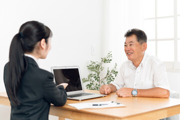 打ち合わせするスーツ姿の女性と高齢者男性
